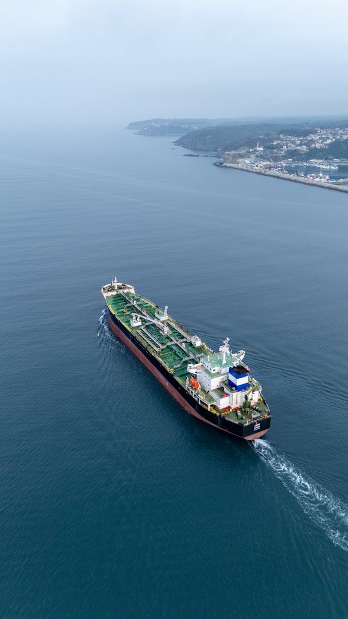 Aerial view of a cargo ship sailing near the coastline on a calm day.