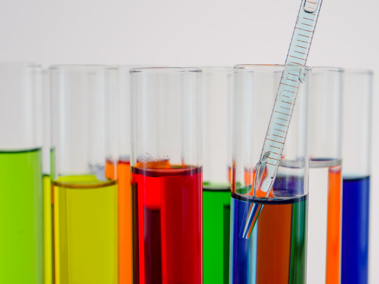 Close-up of colorful test tubes with a glass pipette in a laboratory setting.